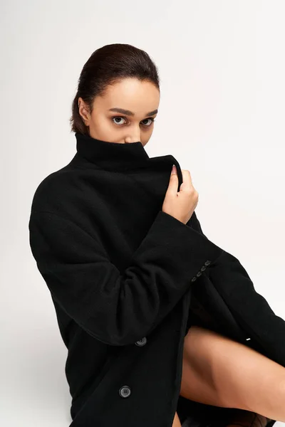 Молодая женщина излучает уверенность в стильной черной одежде, демонстрируя свое уникальное чувство моды. — стоковое фото