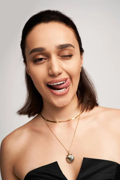 Modelo morena posa juguetonamente en traje negro de moda, exudando confianza y encanto. - foto de stock