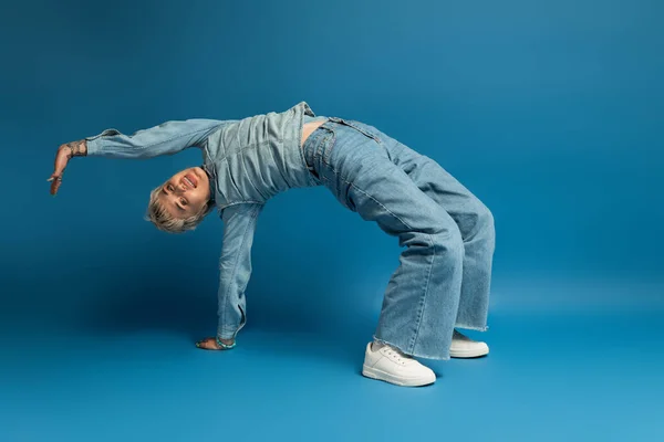 Eine junge Frau beugt sich freudig in stylischen Jeans und zeigt ihre Energie und ihren Sinn für Mode. — Stockfoto
