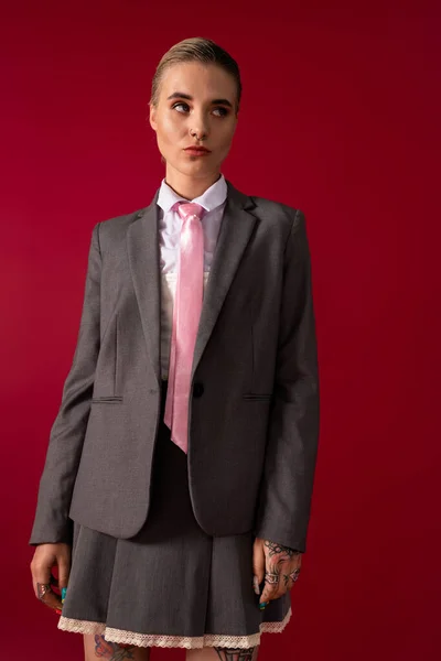 Впевнена молода жінка в шикарному вбранні позує на сміливому червоному тлі. — стокове фото