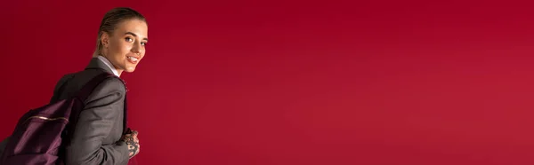 Une jeune femme confiante vêtue d'une tenue élégante porte un sac à dos tout en souriant vivement. — Photo de stock