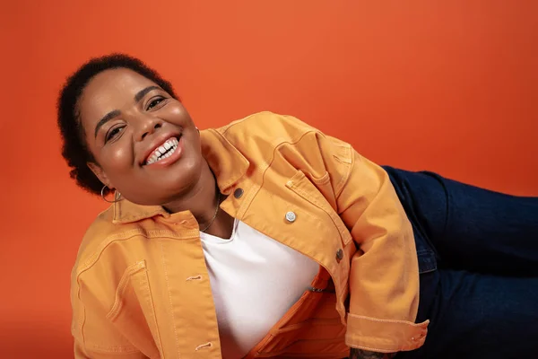 Необыкновенная афроамериканка моделирует свой модный осенний наряд на оранжевом фоне.. — стоковое фото