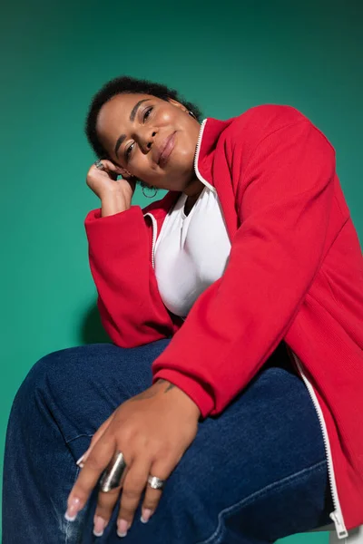 Уверенная в себе чернокожая женщина plus-size позирует в триумфальном осеннем наряде на фоне яркого задника. — стоковое фото