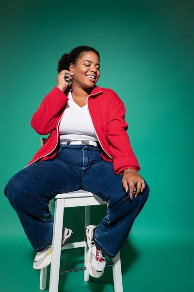 Mujer confiada más tamaño muestra traje de otoño de moda con colores vibrantes en el entorno del estudio. - foto de stock