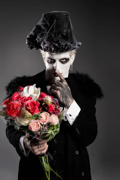 Um jovem bonito abraça o espírito de Halloween com um traje dramático, segurando rosas na mão. — Fotografia de Stock