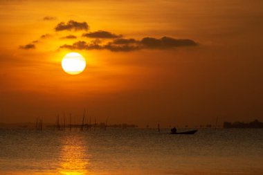 Büyük güneş ve günbatımı göl suyuna yansıyor..