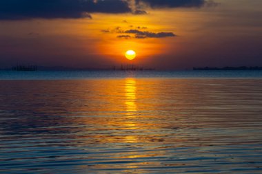 Küçük Güneş ve su göl günbatımı gökyüzü yansıması.