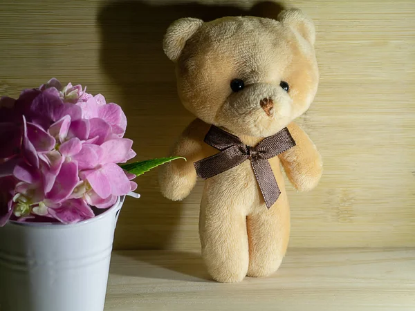 Close up bear and pink Hydrangea flower in white bucket on wooden background with light and shadow.