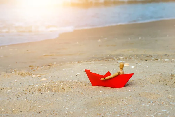 木制模特感到孤独在红色的小船在海滩与阳光 — 图库照片
