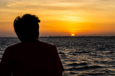 Yalnız bir adam silüeti gölde günbatımı arıyoruz.