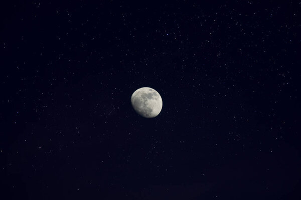 The moon on the deep blue sky in the night with stars background.