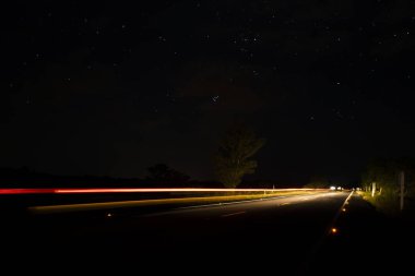 Karanlık gece yolda arabanın hareket ışığı.