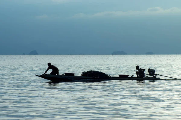 Mavi bir saat içinde en az balıkçı teknesi göl kenarında silüeti. — Stok fotoğraf
