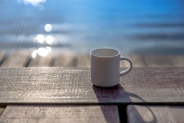 Beyaz kahve kupası, ahşap üzerine, sabah bulanık arkaplan..