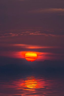 Bulutlu ve siluetli gün batımı gökyüzü altın çağda gölde..