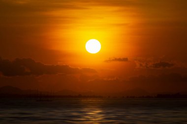 Bulutlu ve siluetli gün batımı gökyüzü altın çağda gölde..