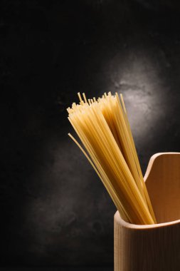 sarımsak siyah yüzeyi ile tahta kap içinde pişmemiş spagetti avuç