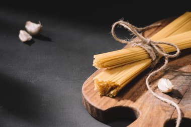 sarımsak ahşap kesme tahtası ve siyah yüzey ile bağlı spagetti yakın çekim shot