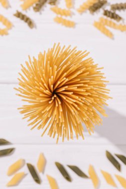 Grup çiğ spagetti makarna diğer türleri ile beyaz ahşap masa üzerinde yukarıdan