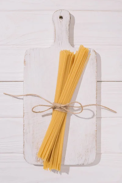 Bovenaanzicht Van Spaghetti Vastgebonden Met Draad Liggend Witte Houten Snijplank — Stockfoto