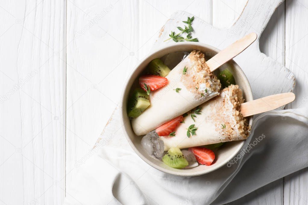 Delicious popsicles with strawberry and kiwi in bowl