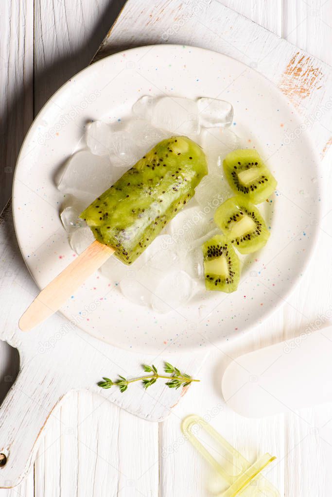 Kiwi ice pop on plate with ice cubes