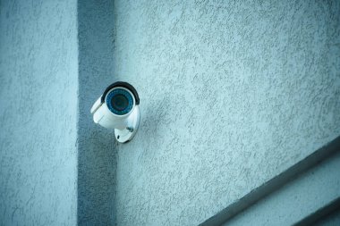 close up view of security camera on gray building facade clipart