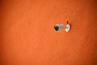 close up view of security camera on orange colored building facade