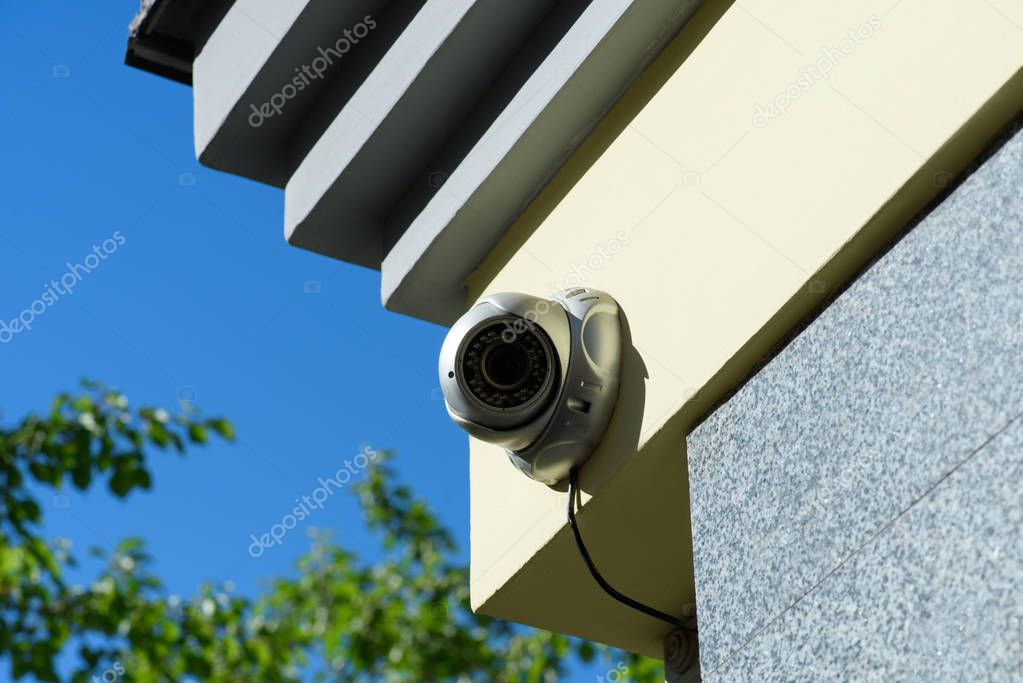 close up view of security camera on building facade in sunlight