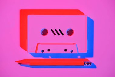 toned pink picture of retro audio cassette and pencil on tabletop clipart
