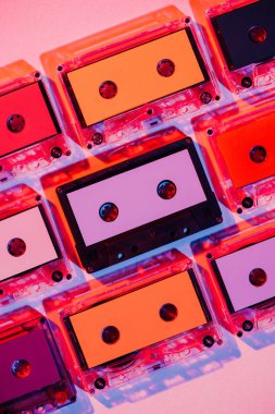 toned picture of colorful retro audio cassettes on pink background clipart