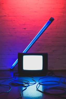 toned picture of arranged retro tv set, cables and lamp with brick wall background clipart