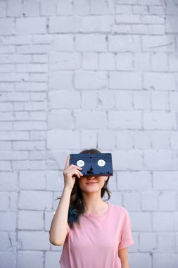 kadının gözleri retro video kaset ile el Beyaz tuğla duvara kapsayan gizlenmiş görünümü