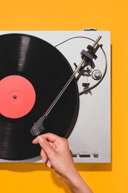 cropped shot of woman turning on vinyl player isolated on yellow clipart