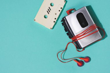 flat lay with retro audio cassette, cassette player and earphones isolated on blue clipart