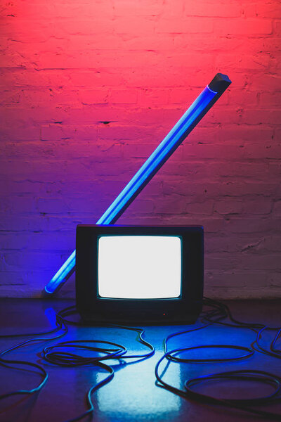 тонированное изображение ретро-телевизора, кабелей и лампы на фоне кирпичной стены
