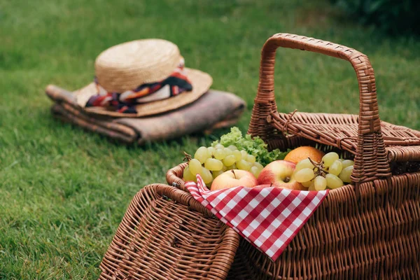 ピクニックで緑の芝生の上のバスケットにおいしい果物 — ストック写真