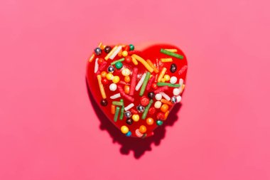 sprinkles ile kırmızı kalp şeklinde lezzetli şeker pembe üzerinde yukarıdan