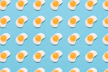 top view of tasty gummy candies in shape of fried eggs on blue clipart