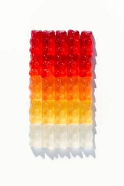 top view of composition of gummy bears in shape of gradient rectangle on white clipart