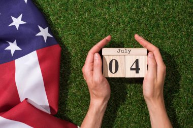 cropped shot of man holding calendar with 4th july date with american flag on green grass, americas independence day concept clipart