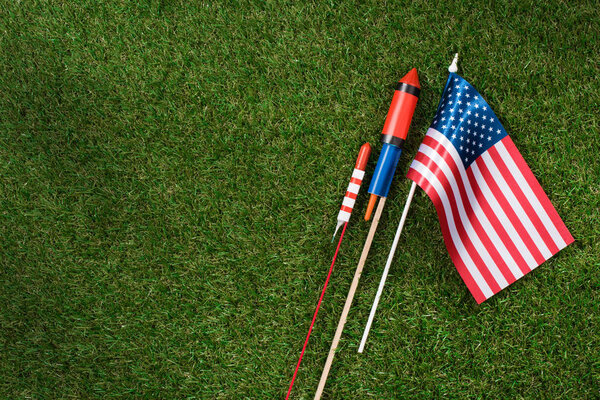 flat lay with american flagpole and fireworks on green grass, americas independence day concept