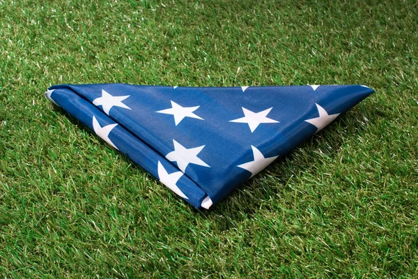 close up view of folded american flag on green lawn, americas independence day concept