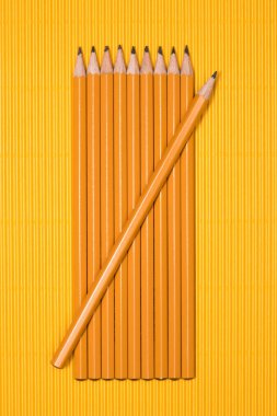 elevated view of graphite pencils placed in row on yellow  clipart
