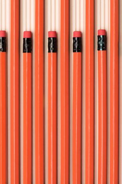 top view of red graphite pencils with erasers placed in row on beige  clipart