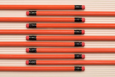 view from above of red graphite pencils with erasers placed in row on beige  clipart