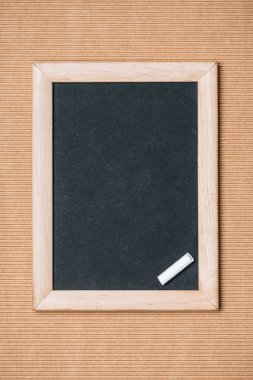 top view of empty blackboard and piece of chalk on brown background  clipart