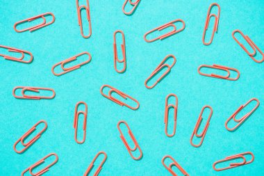 full frame of arranged red paper clips on blue background clipart