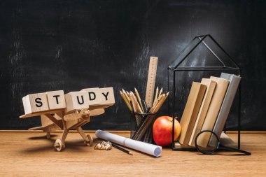ahşap oyuncak uçak görünümünü kapatın, yazıt blokları, kitaplar ve kalem boş yazı tahtası ile masa üzerinde yapılan çalışma