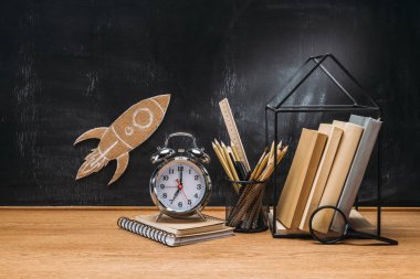 karton roket bakış yazı tahtası, kalem, saat, Not defteri ve ahşap masa kitap üzerinde kapatın